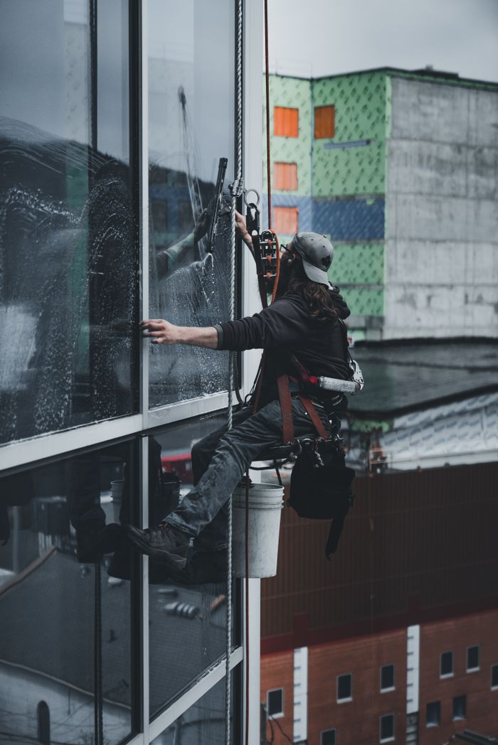 about-us-01 A man in a harness cleaning skyscraper windows with precision.
